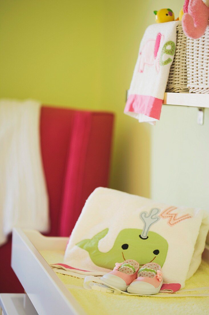 Handtuch mit Wahlfisch-Motiv und Babyschuhe auf einem Wickeltisch