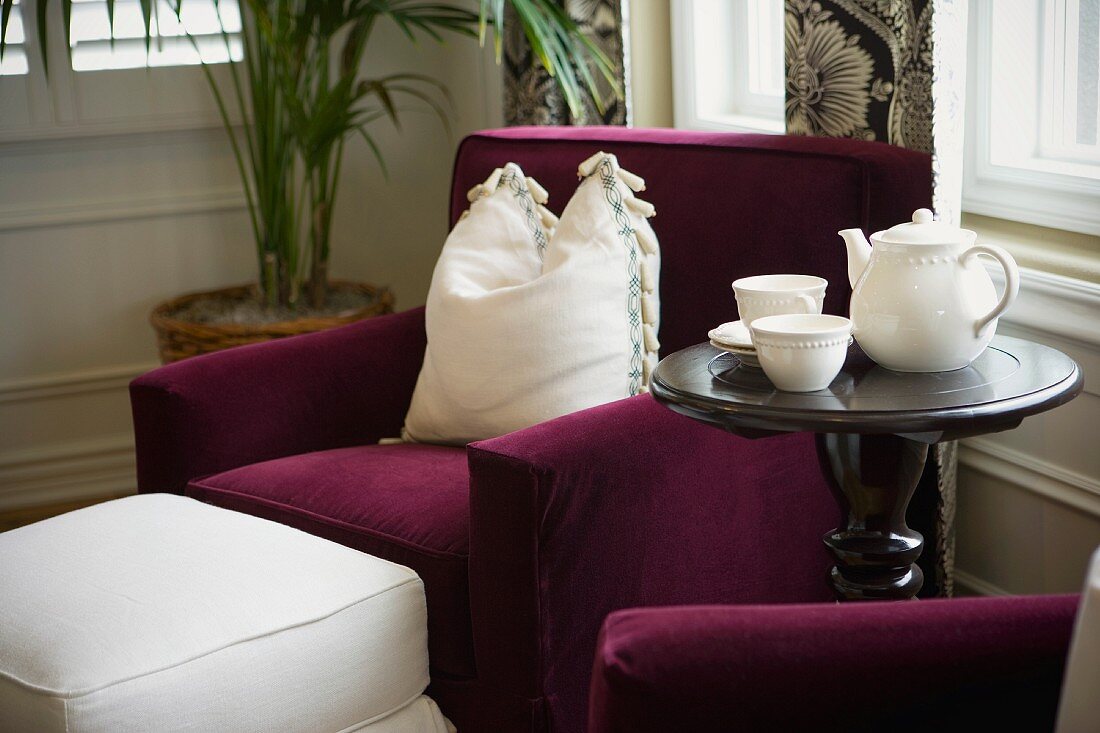 Vignette of purple chair with white pillow and tea set
