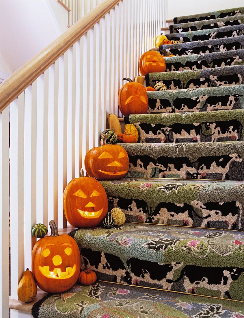 Treppenaufgang mit lustigem Treppenläufer und einer Halloweendekoration auf jeder Stufe