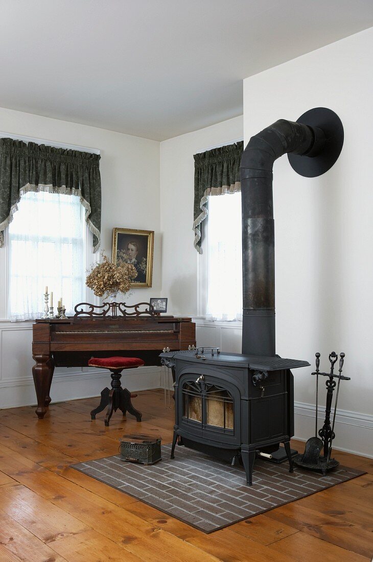 Black wood-burning stove next to antique piano and swivel stool