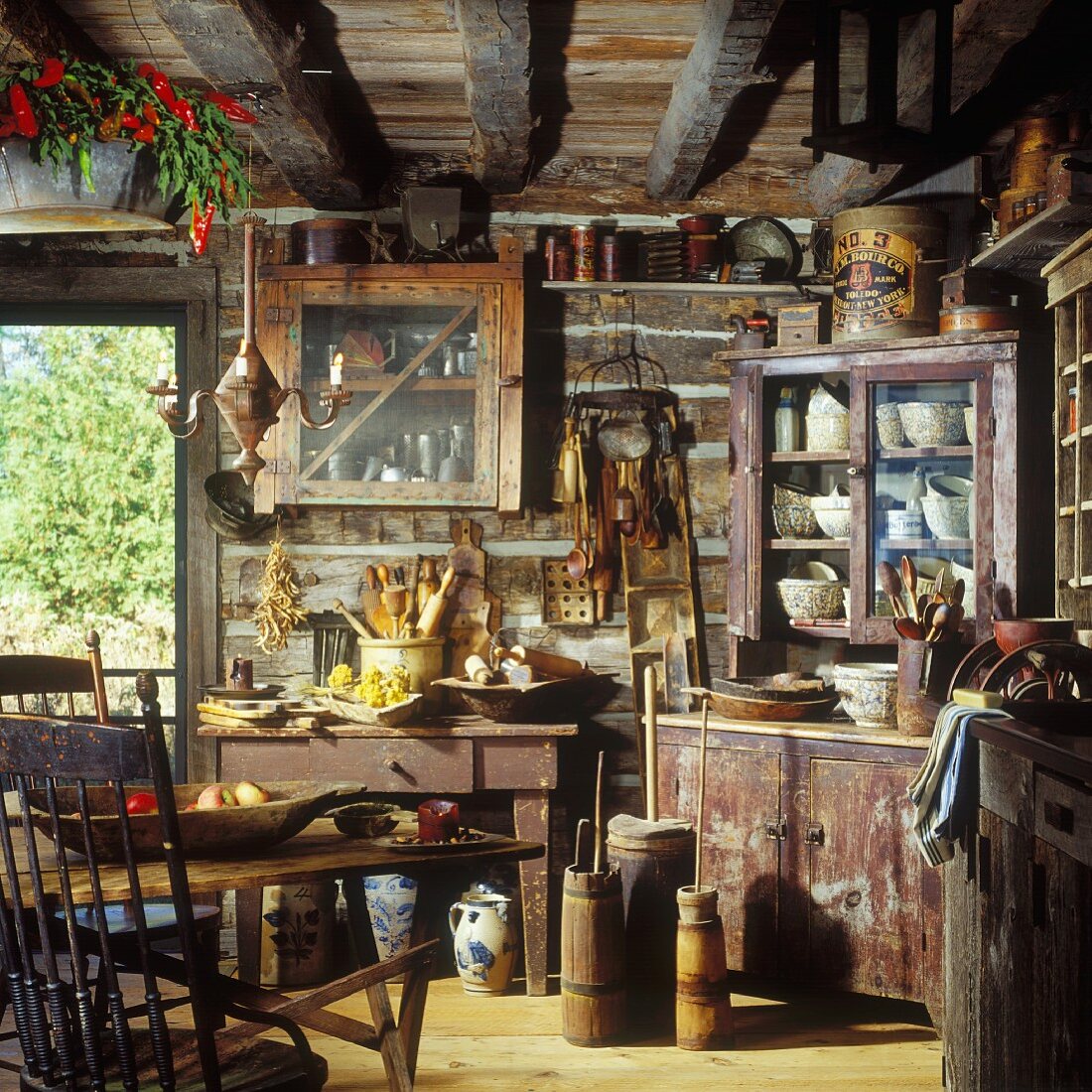 Kitchen in rustic log cabin with wood-beamed ceiling and antique kitchen utensils
