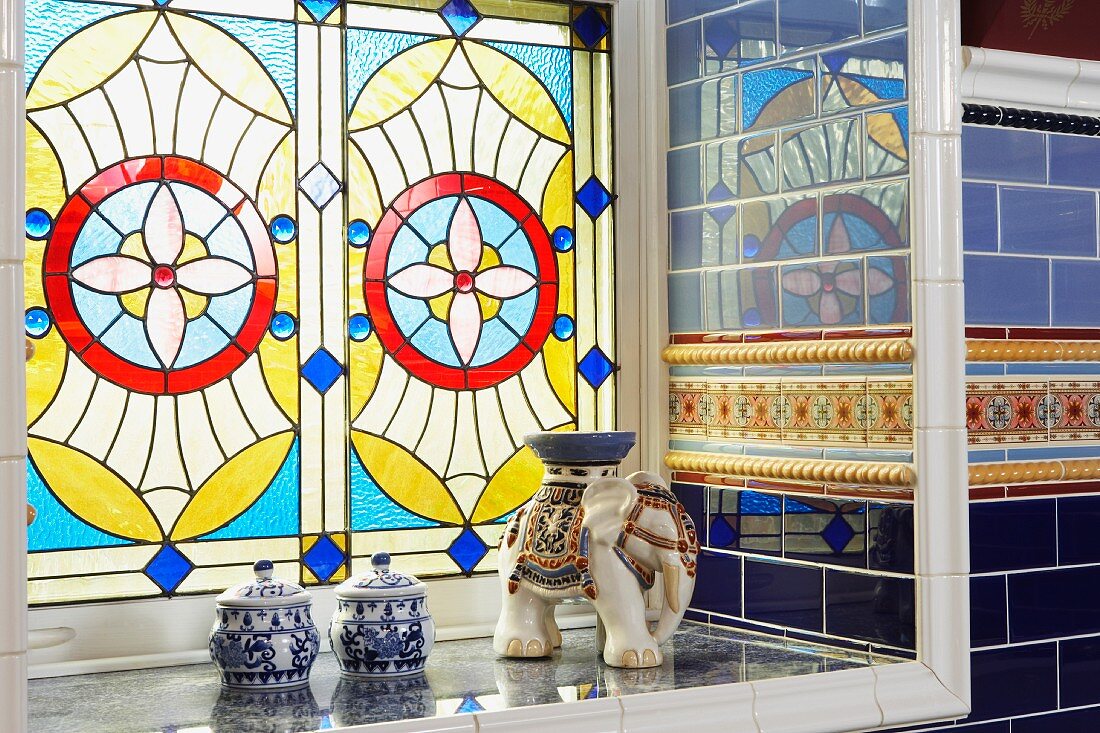 Stained and leaded glass window in Victorian bathroom with reflective wall tiles