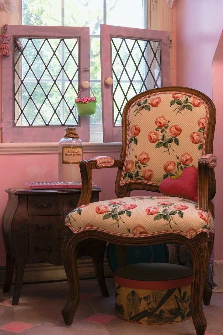 Polsterstuhl mit Armlehnen und Rosenmuster in einem rosa Raum