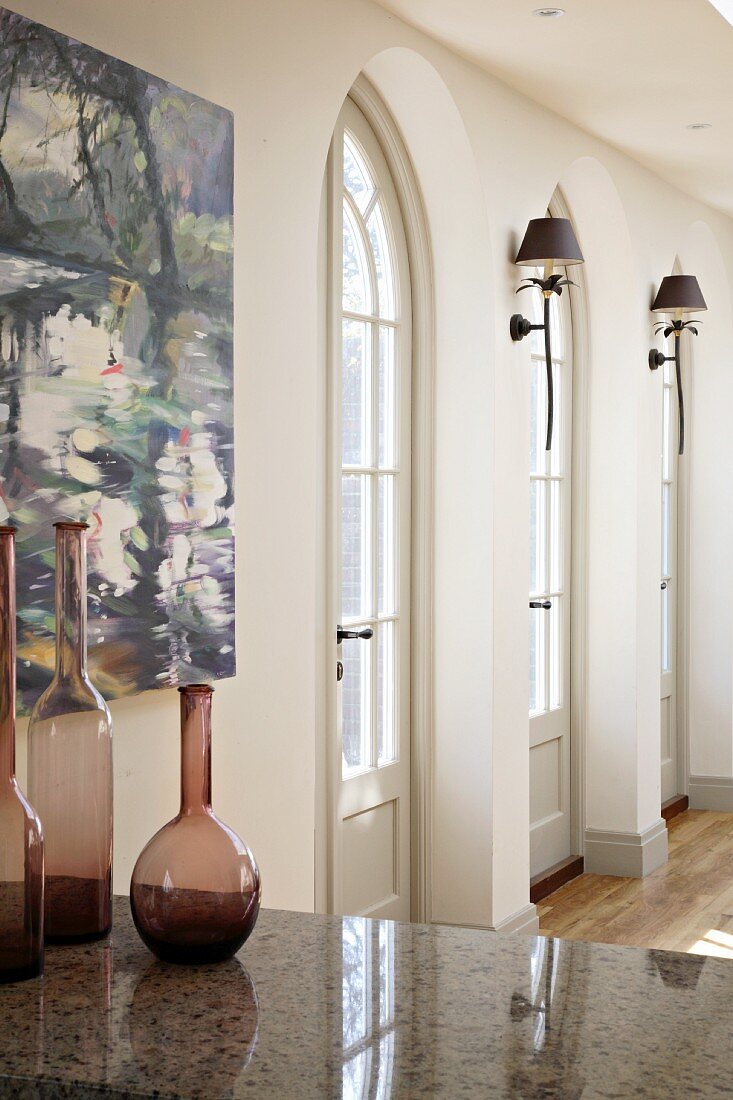 Terrace doors with rounded arches and decorative bottles on stone table in traditional interior