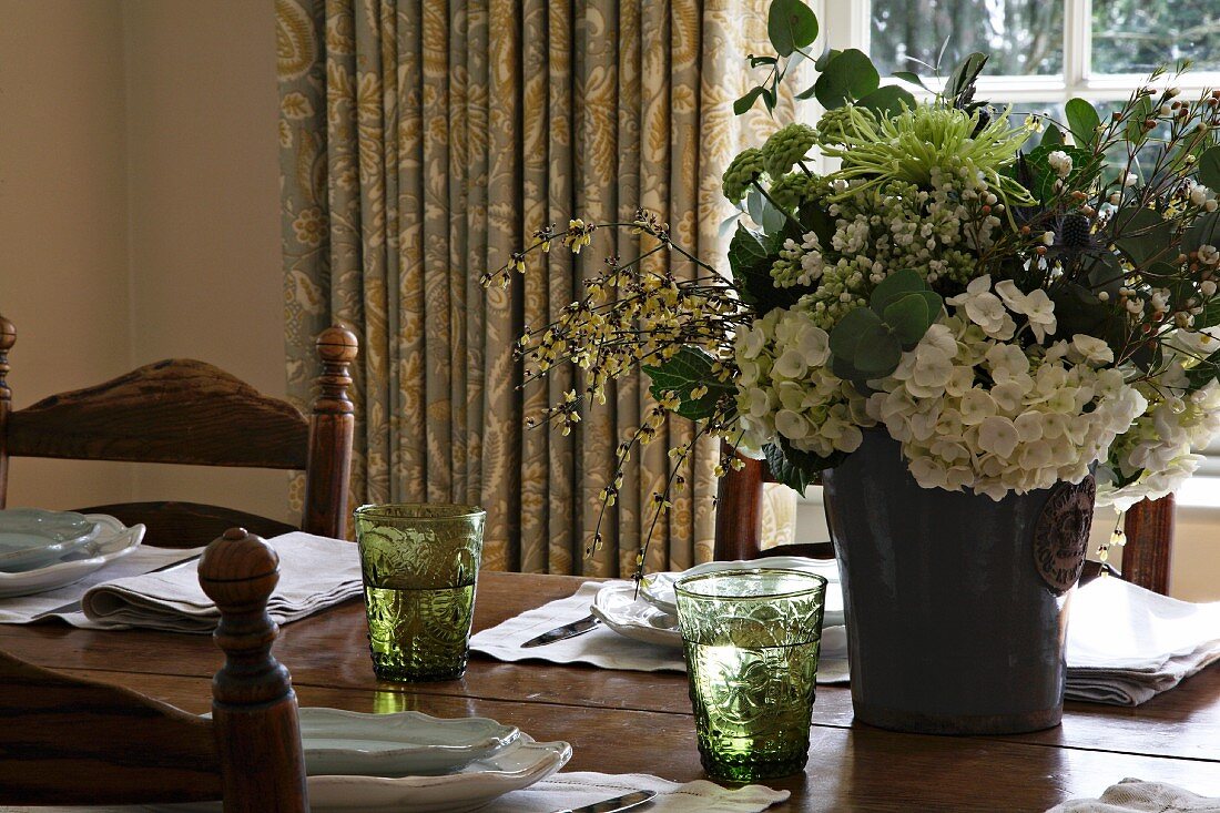 Blumenstrauss und Gedecke auf Esstisch aus Holz