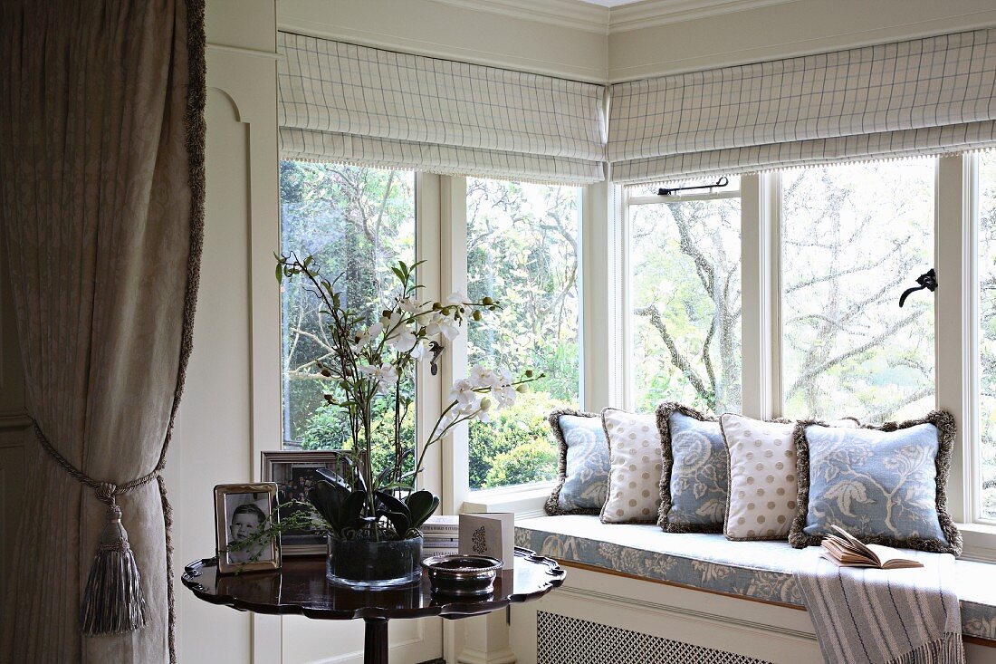 Gemütliche Fensterbank mit Aussicht und Beistelltisch mit Orchidee im Topf
