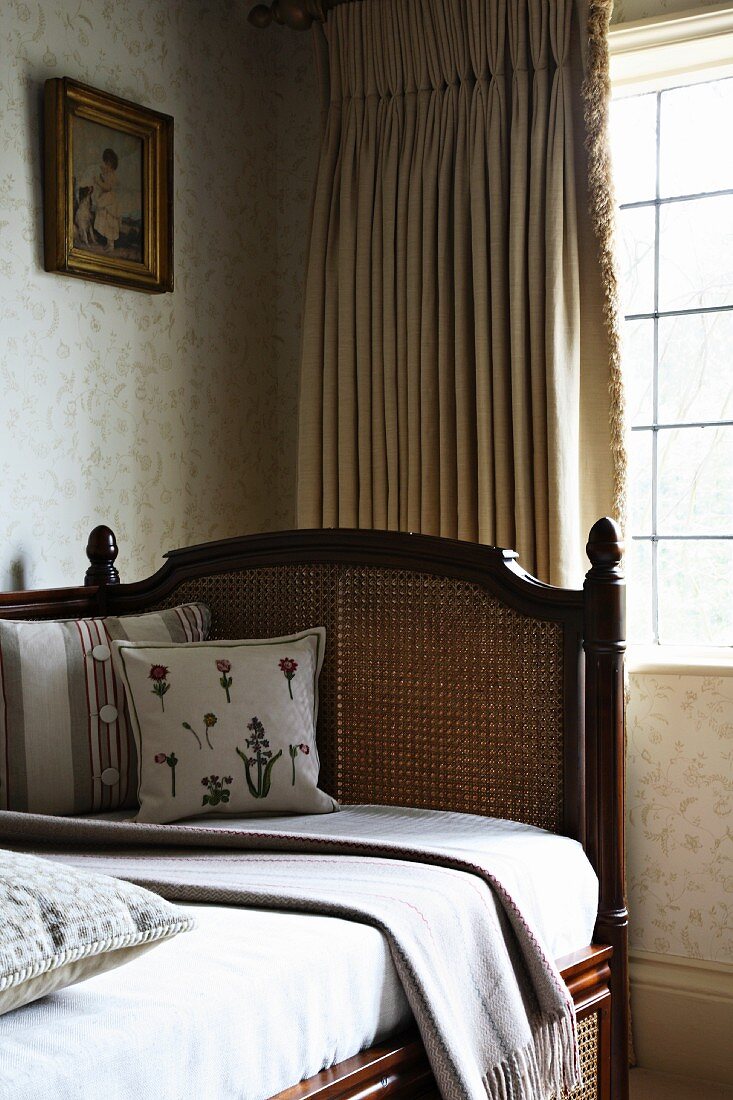 Traditionelles Tagesbett mit Lehne vor Fenster mit Vorhang