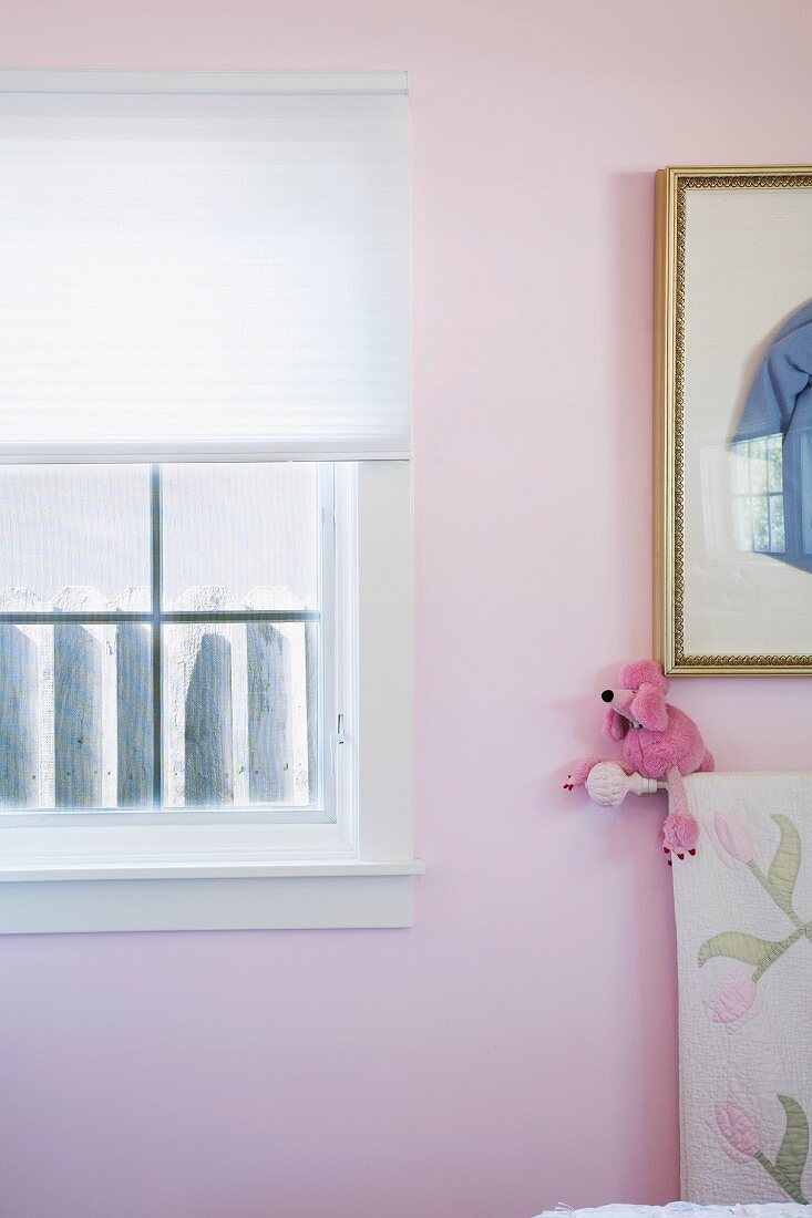 Ausschnitt eines Mädchenzimmers mit rosa Wand und Fenster mit halbgeschlossenem Rollo