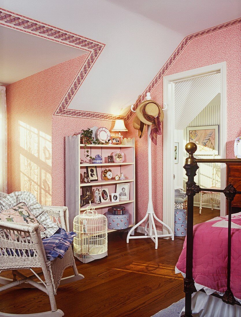Weisses Dekoregal in Kinderzimmer mit rosa Tapete und einem weissen Schaukel-Korbstuhl