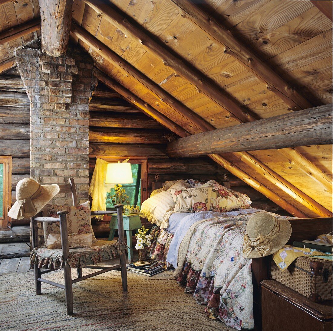 Rustikaler Schlafraum unter dem Dach mit alter Balkendecke, Holz- und Backsteinwand und einem Einzelbett mit gemusterten Kissen und Decken