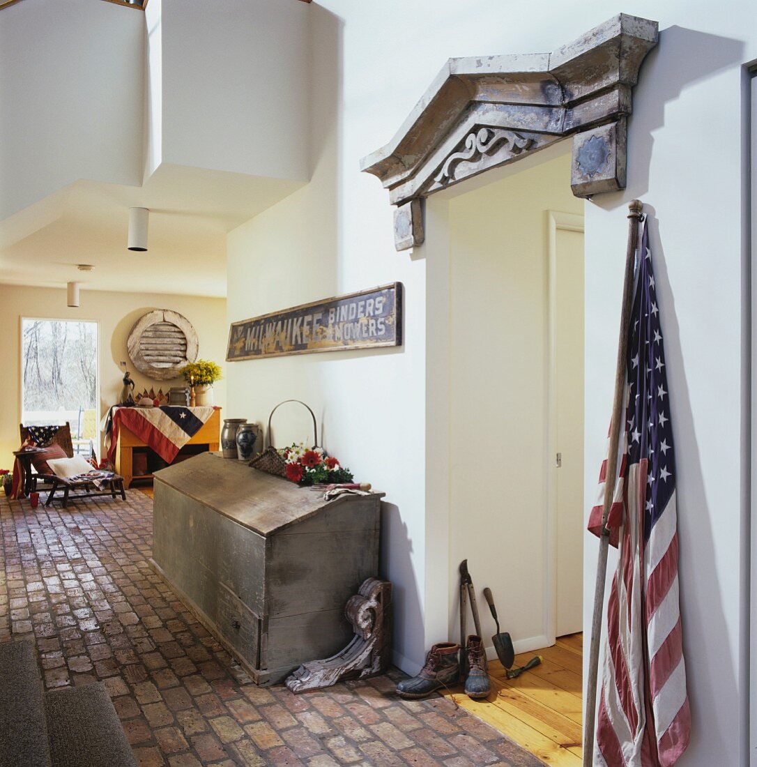 Hallway with terracotta tiles and doorway with wooden frieze decorated with antiques and flags from the American Civil War