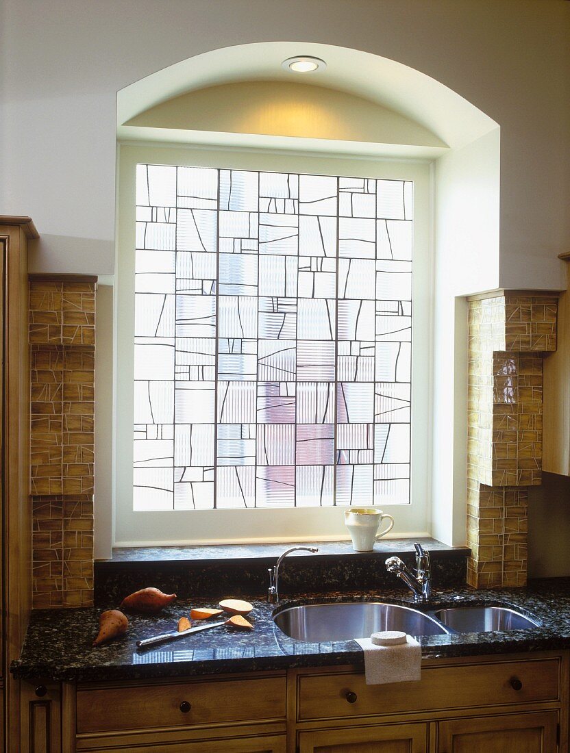 Bleisglasfenster und Rundbogen über der Spüle mit Marmorplatte in einer Küche