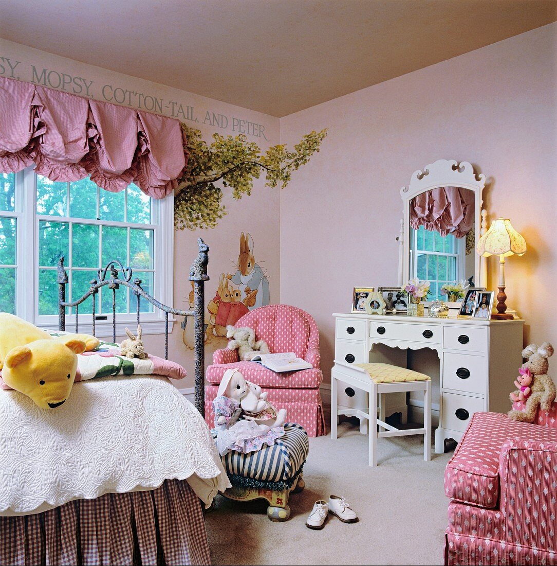 Charming child's bedroom in shades of pink with playful dressing table and whimsical mural