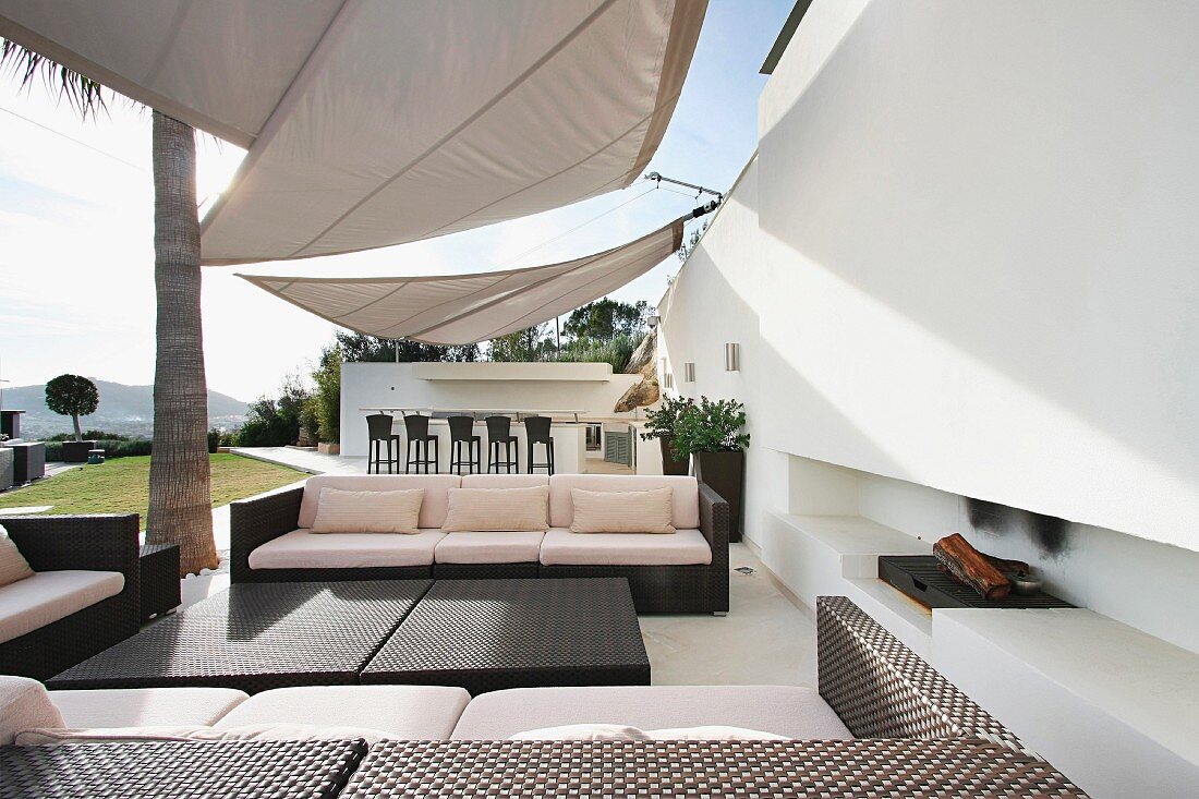 Designer Outdoor Möbel auf Terrasse mit Sonnenschutzsegeln vor zeitgenössischer Architektur