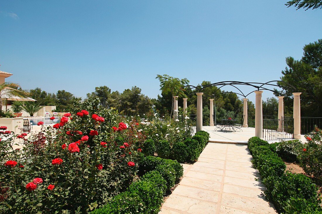 Blühender Garten mit elegantem, kreisförmigen Freisitz und Pergola auf Säulen
