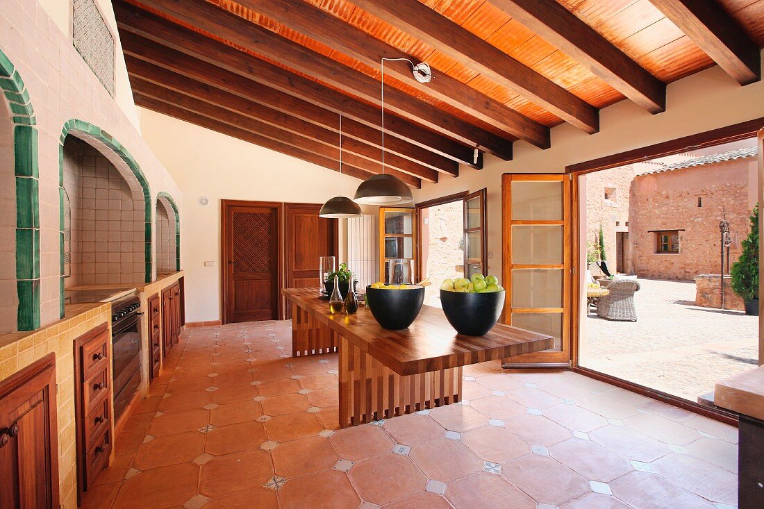 Esszimmer mit modernem Tisch und traditionellem Fliesenboden in mediterranem Landhaus mit offener Terrassentür