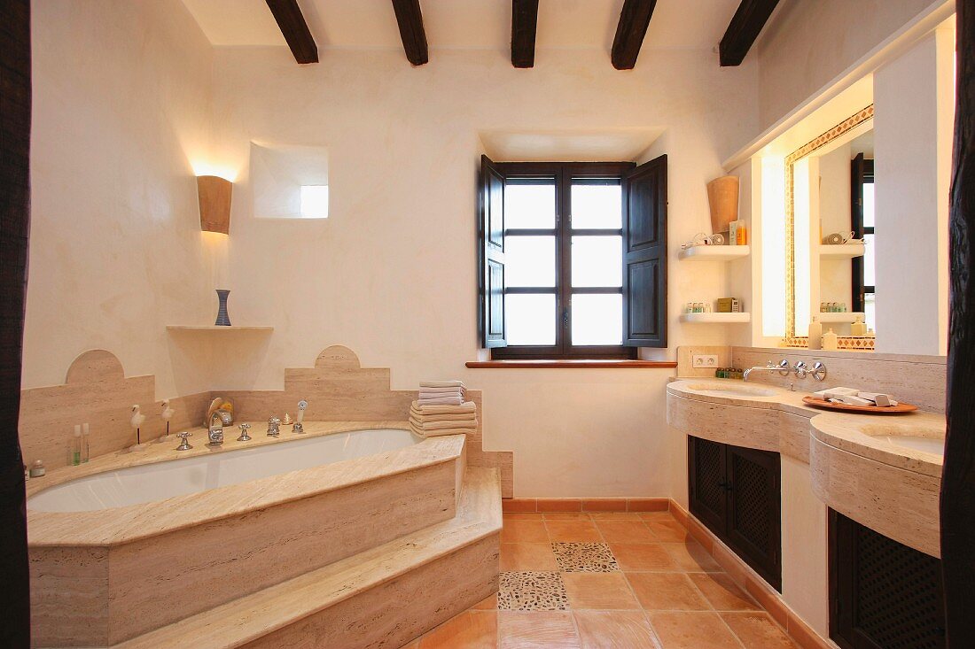 Eckbadewanne mit Stufen und Waschtisch in elegantem Bad eines mediterranen Landhauses
