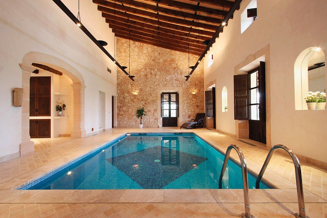 Indoor Pool in mediterranem Landhaus mit Rundbogenfenstern und Natursteinwand