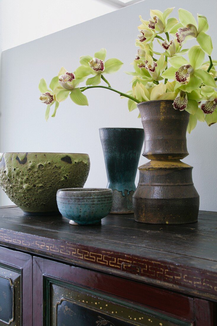 Schalen und Vase mit Orchideen auf einem antiken Schrank