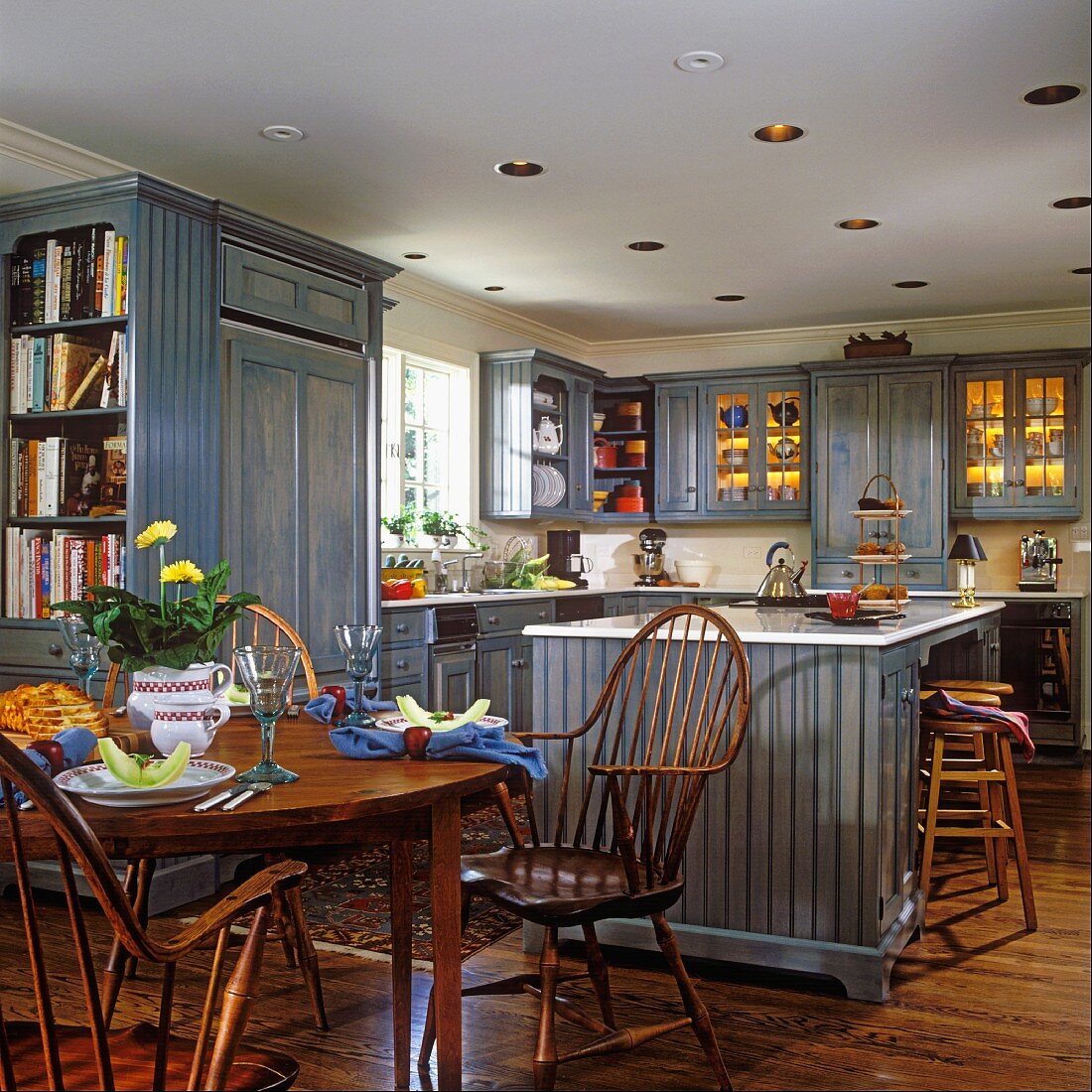 Offene Küche mit rundem Esstisch und Stühlen aus Holz und blauen Küchenschränken