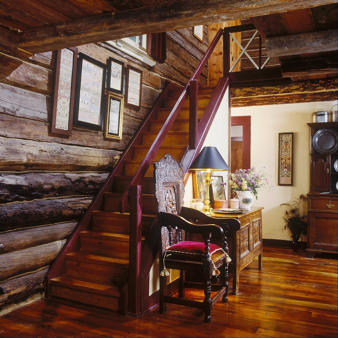 Eingangsbereich eines Bauernhauses mit einem kunstvoll geschnitzten Stuhl an der Treppe