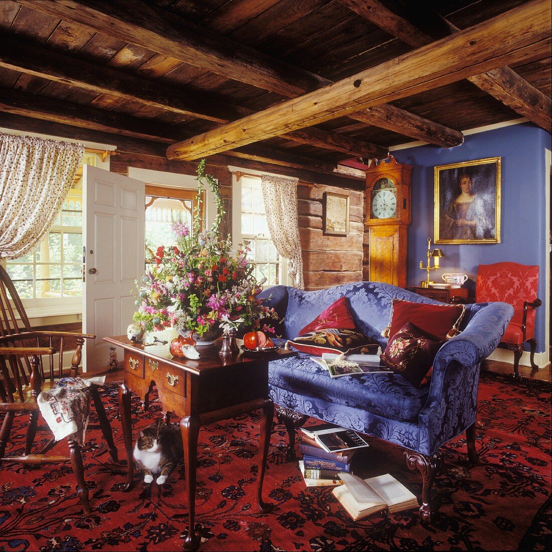 Living room with rustic beamed ceiling, blue sofa, lowboy table and Oriental rug