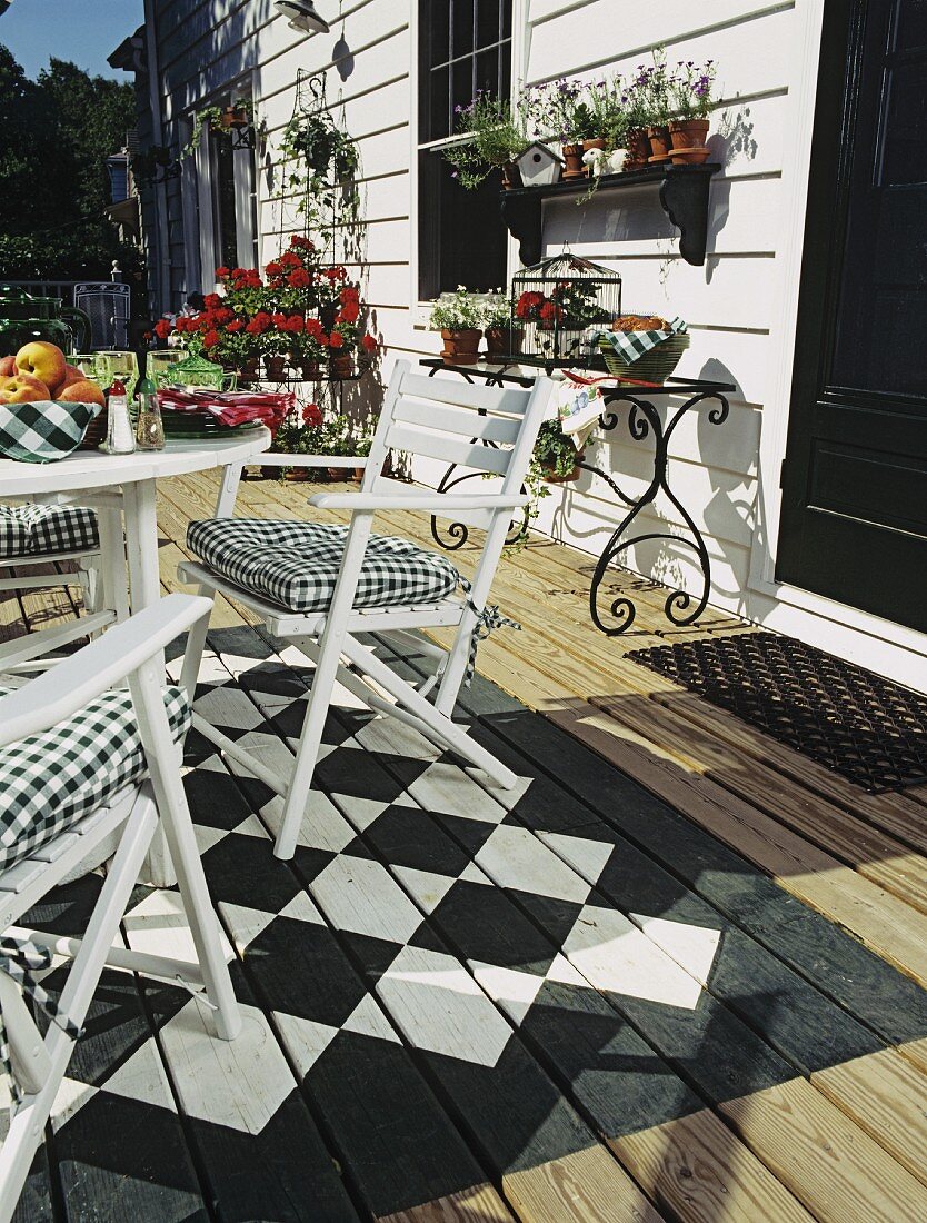 Terrasse mit Tisch, Stühlen, Pflanzen und schwarz-weißem Schachbrettmuster auf dem Boden