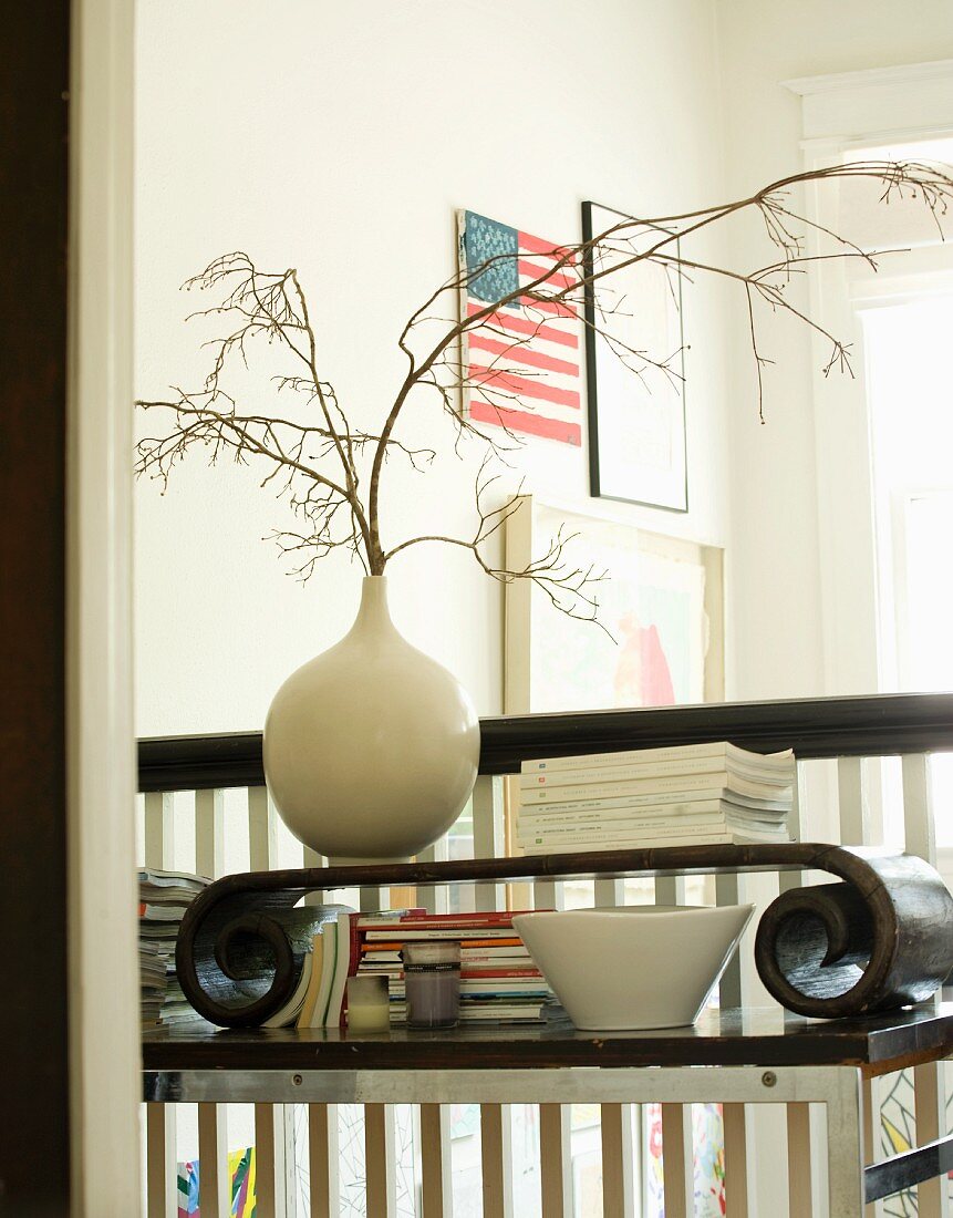 Ablage mit Vase und Büchern vor einem Treppengeländer und amerikanischer Flagge im Hintergrund