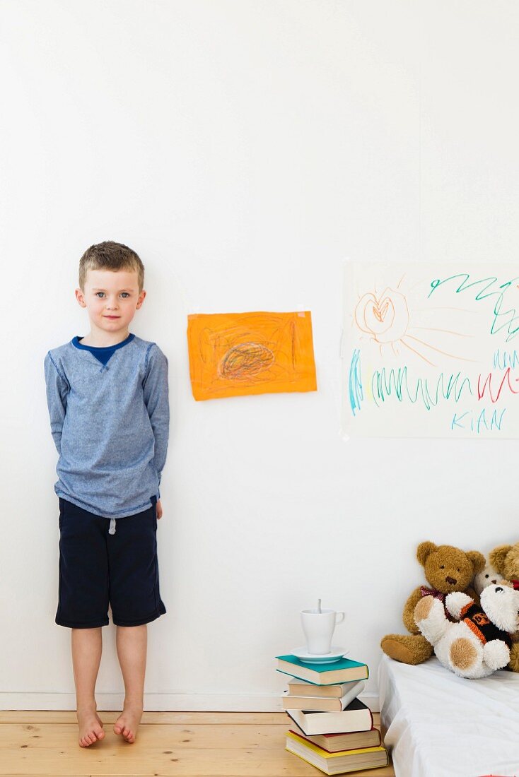 Junge steht an der Wand mit Zeichnungen