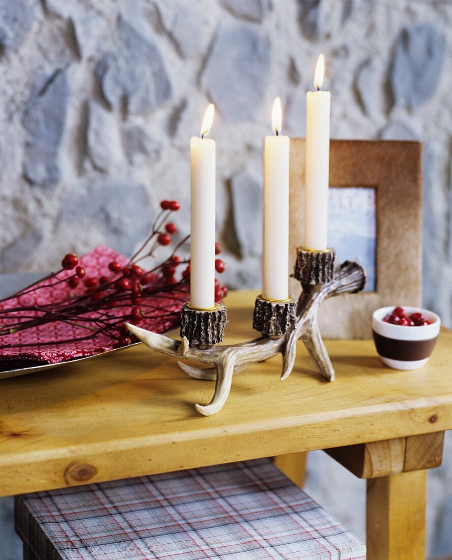 Kerzenständer aus Kunsthorn auf Holzablage vor Paneel in Steinwand-Optik