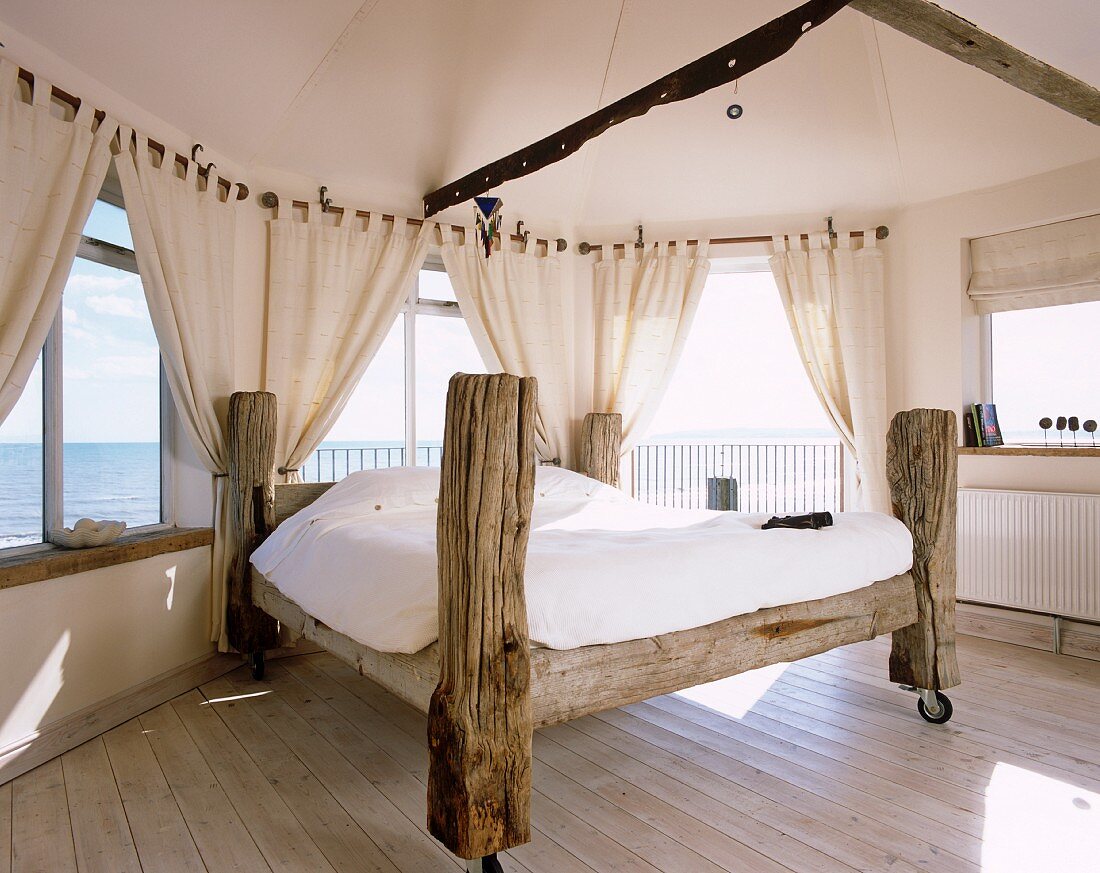 Selbstgebautes Bett aus Baumstämmen und auf Rollen im Schlafzimmer mit Panoramablick
