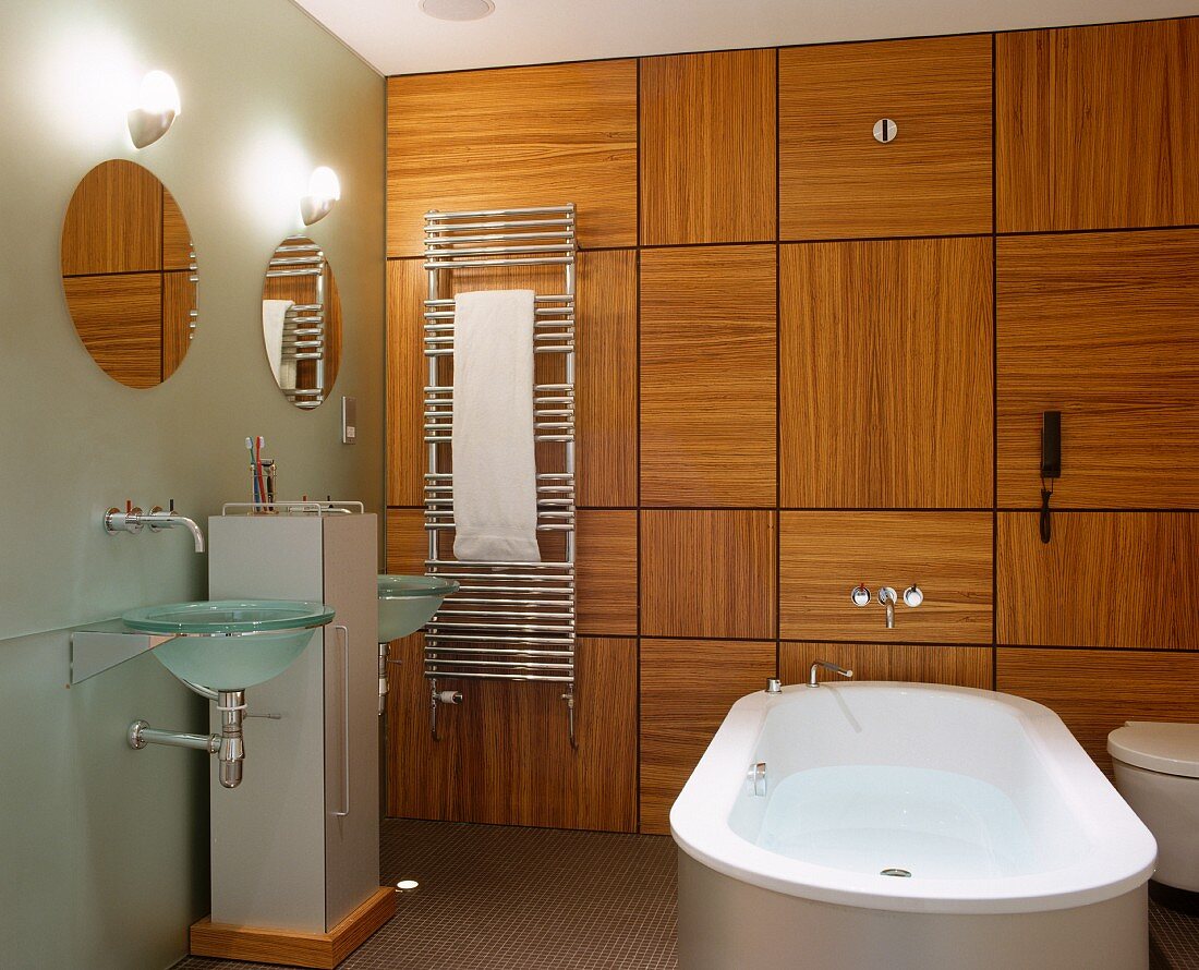 Free-standing bathtub in front of wood-panelled wall in designer bathroom