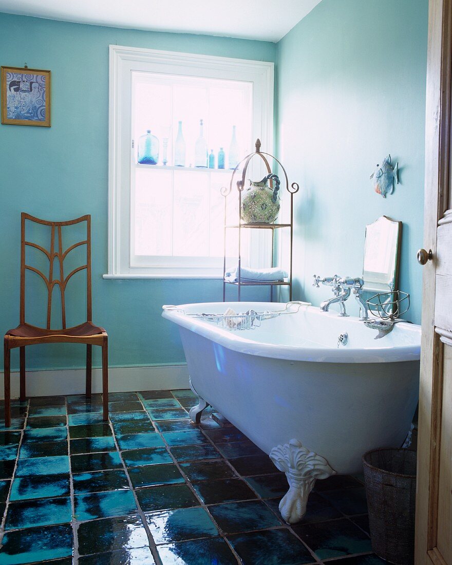 Freistehende Vintage Badewanne vor Fenster und handgefertigte Fliesen auf Boden in traditionellem Ambiente