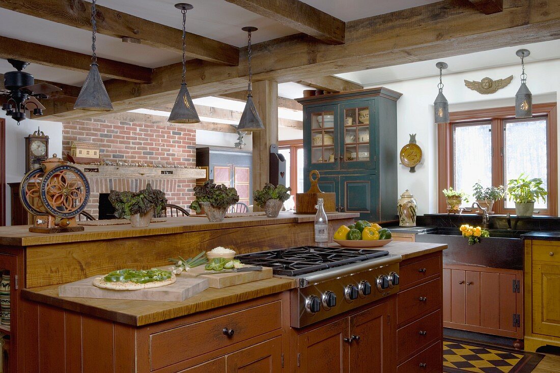 Free-standing kitchen counter with rustic wooden base units in simple country house kitchen