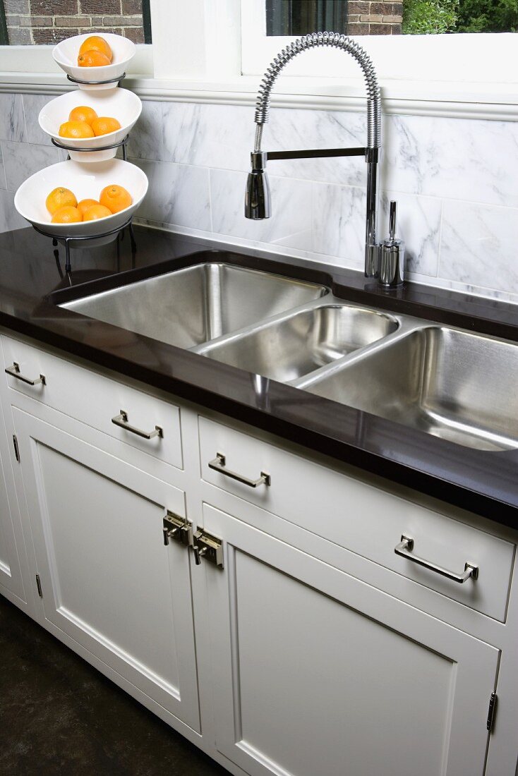 Kitchen counter with stainless steel sinks and white base units in modern country house style