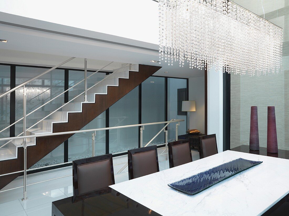 Modern dining room with beaded crystal chandelier and staircase