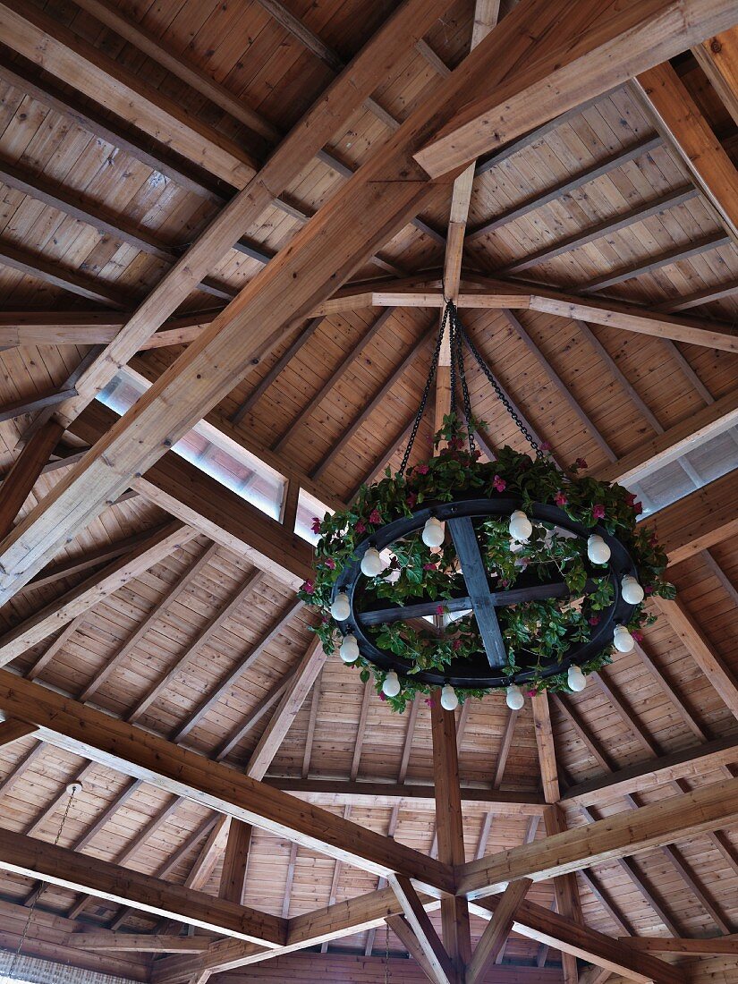 Holzdach mit daran hängendem, runden, geschmückten Kronleuchter