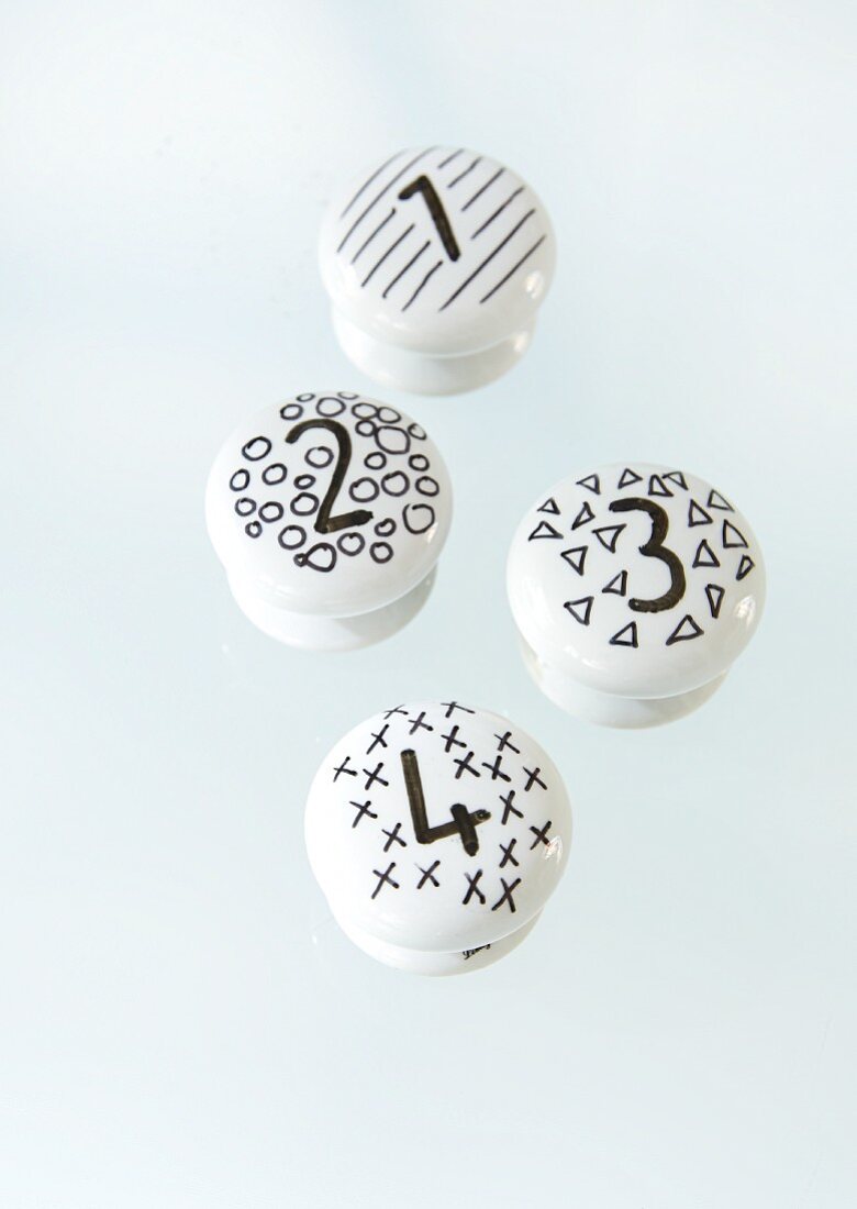 White porcelain knobs decorated with black patterns and numbers