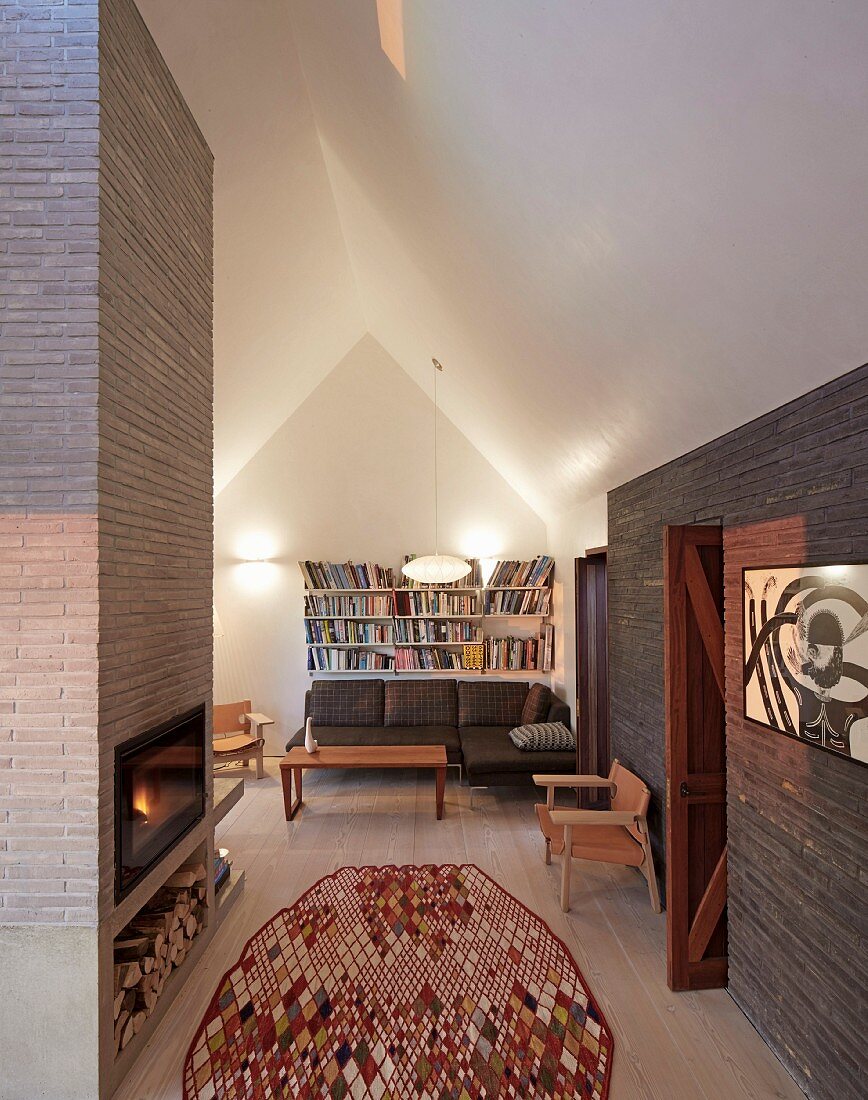 Moderner gemauerter Kamin in gemütlichem Dachgeschoss- Wohnraum mit Dielenboden und Designerflair