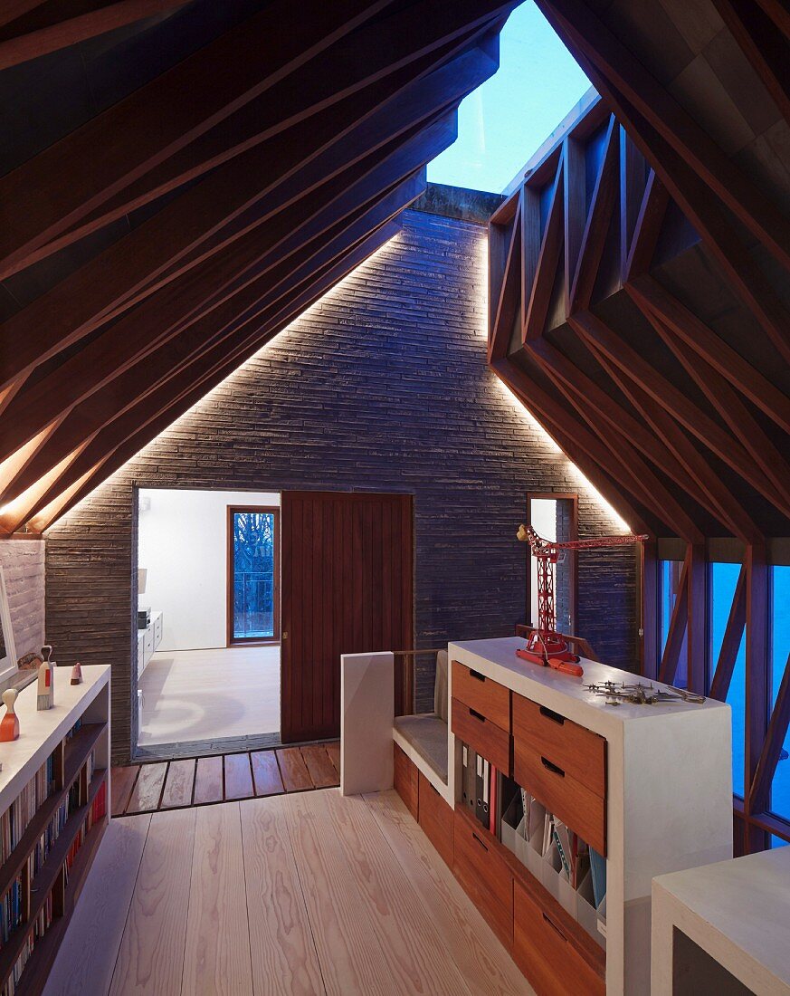 Verglaster First und außergewöhnliche Dachkonstruktion mit indirekt beleuchtetem Sichtmauerwerk auf Galerieebene eines Architektenhauses