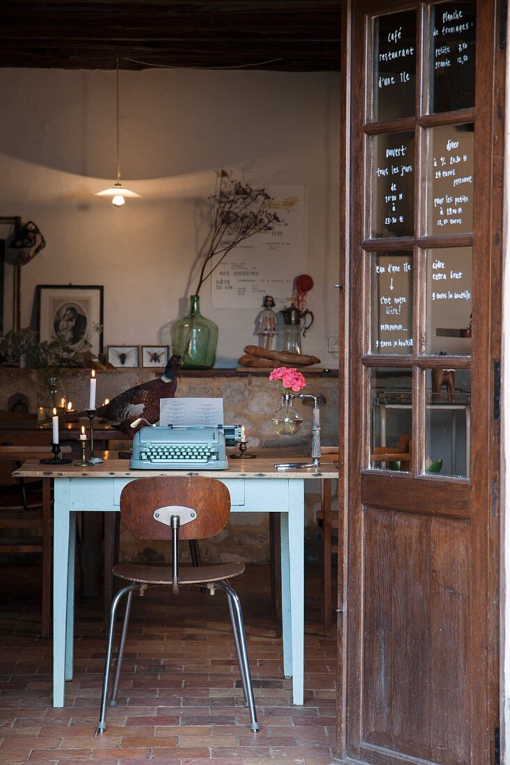Typewriter and candles on wooden table in vintage interior with brick floor