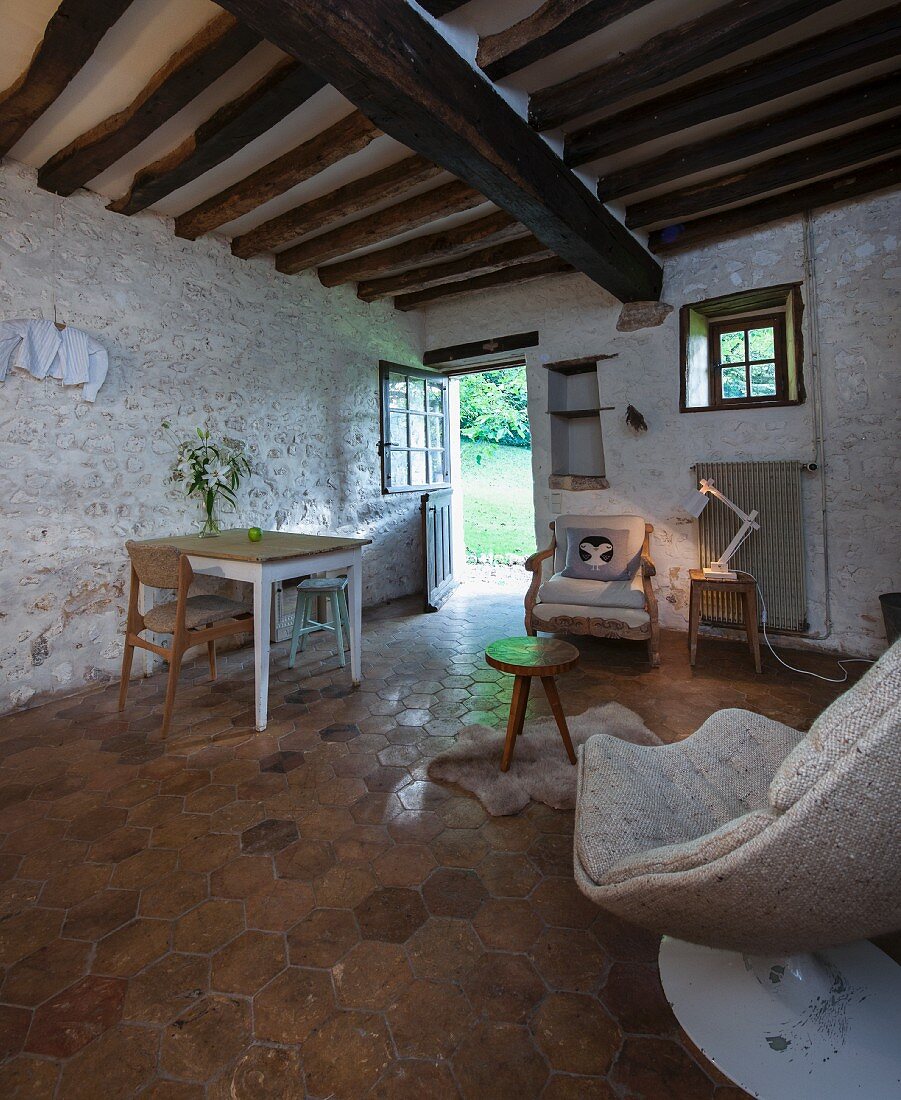 Tiled floor, painted stone wall and rustic wood-beamed ceiling in vintage interior