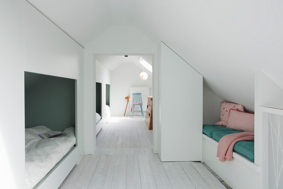 White wooden floor and row of alcoves under sloping ceiling in converted attic