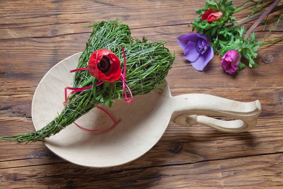 Spring place setting with heart-shaped bundle of bilberry stalks and red anemone flower