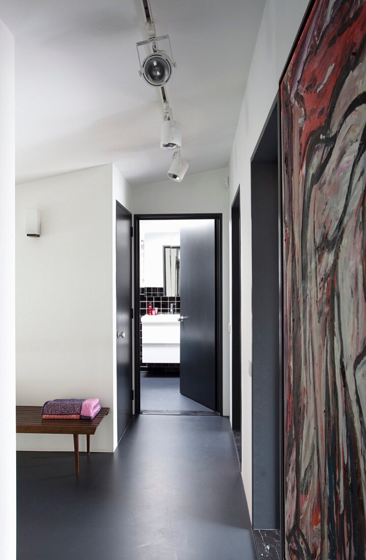 Dark grey epoxy resin floor in foyer with open bathroom door at far end