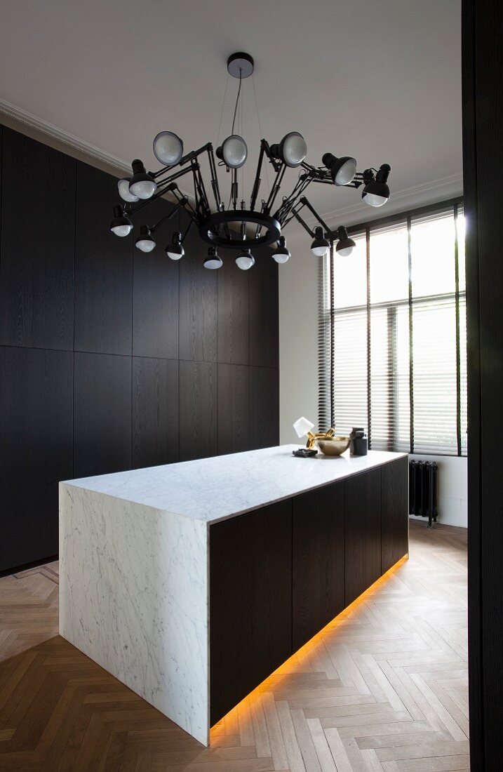 Monolithic counter with indirect lighting in plinth and marble body below pendant lamp with multiple cantilever arms