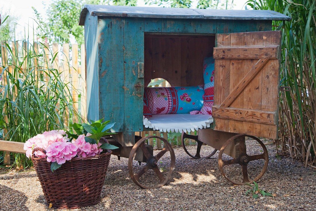 Nostalgischer Leiterwagen mit Vintage-Spielhaus und Korb mit blühenden Hortensien