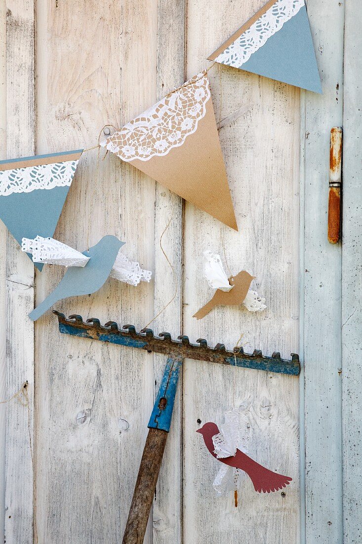 Hand-made bunting with lace trim and paper birds hung on wooden wall