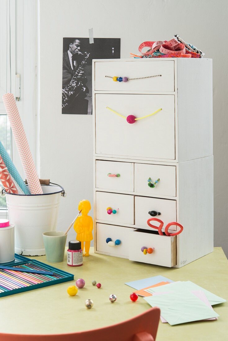 A chest of drawers with homemade knobs and handles made from beads and ribbons