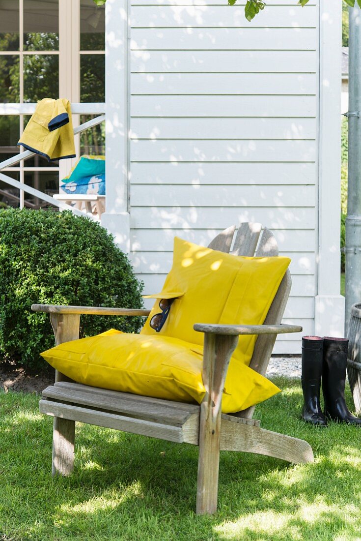 Holzstuhl im Garten mit selbstgemachten Kissenbezug aus gelbem Regenmantelstoff